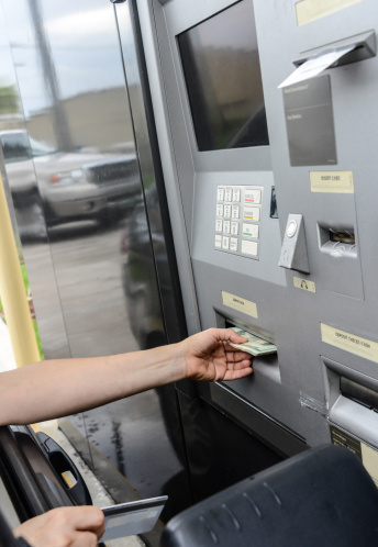caucasian female hand picking the cash from an ATM driving her car