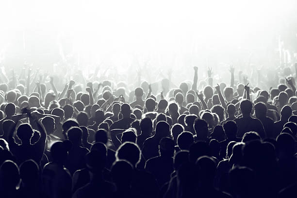 Concert crowd Crowd cheering and watching a band on stage, blinded by stage lights. applauding photos stock pictures, royalty-free photos & images