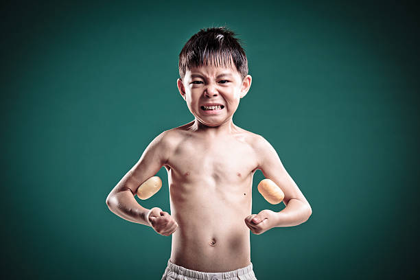 маленький мальчик imagines он содержит силу мышц. - flexing muscles little boys human muscle strength стоковые фото и изображения