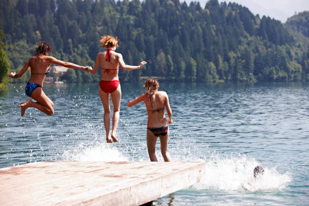 istock Three women in mid air jumping into lake 155445320