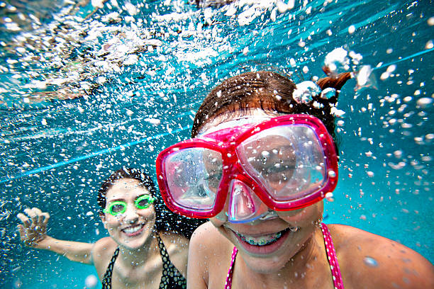 istock Mother and daughter smiling underwater in pool 155445341
