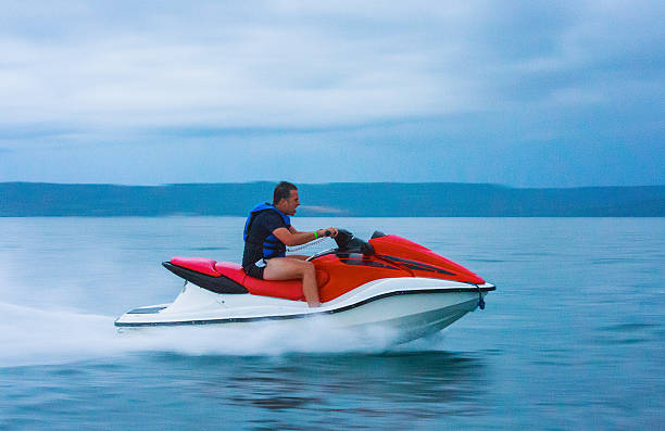 man ridding a jet ski man ridding a jet ski in guanacaste, costa rica - panning, motion blur jet boat stock pictures, royalty-free photos & images