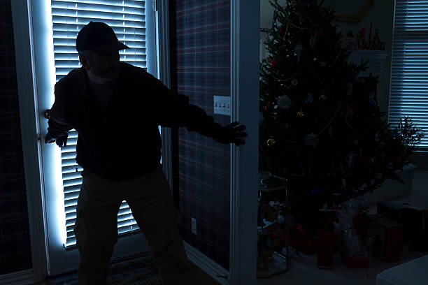 Silhouette of burglar breaking into house at Christmas stock photo