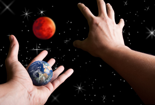 male hand is reaching out to grab planet Mars while other holding earth ,colonization concept