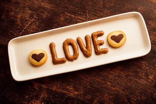 chocolate sweets in the form of a heart with fruits and nuts on a colored background. top view with space for text, holiday concept.