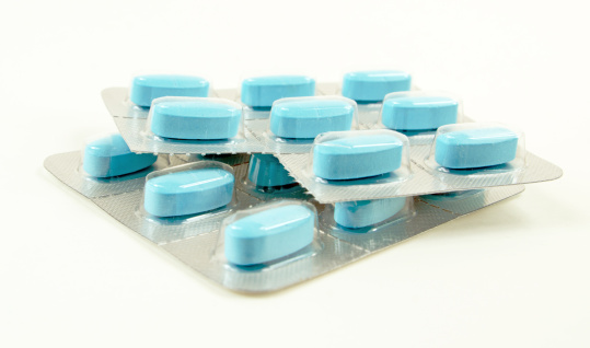 Blue pills sealed in plastic and isolated on white. One pill is missing.
