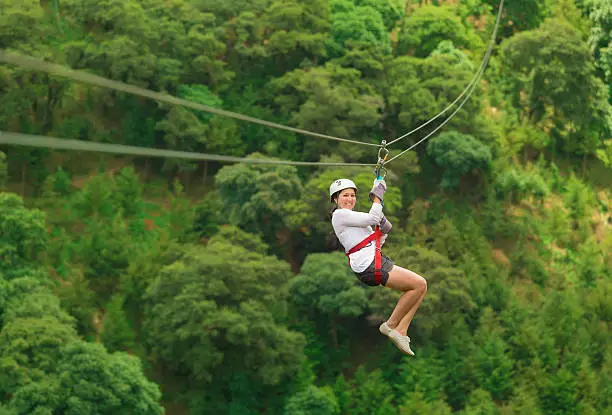 woman in her 40s doing a zip-line Tour Guatemala, zip lines between two hills.