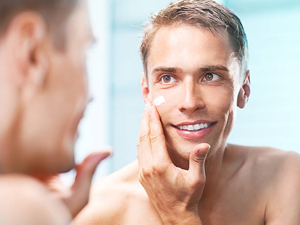 istock young man applying a face cream front of the mirror 155446910