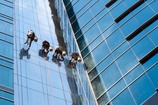 A team of window washers clean the exterior of an urban highrise building.