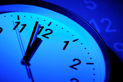 Blue tinted image of clock face that reaches deadline on calendar.