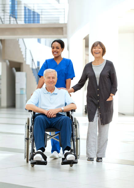enfermeira ajudando um paciente em cadeira de rodas e sua esposa, - hhpm27 imagens e fotografias de stock