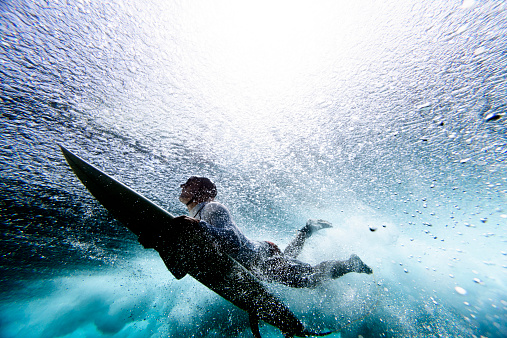Surfer duck diving under reef break