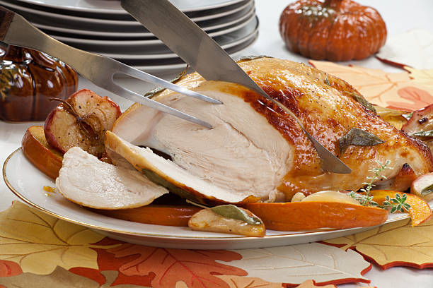 Thanksgiving Turkey breast with sage and honey rub being cut Carving sage - honey butter rub turkey breast garnished with roasted pumpkin and apples in fall themed surrounding. carving set stock pictures, royalty-free photos & images