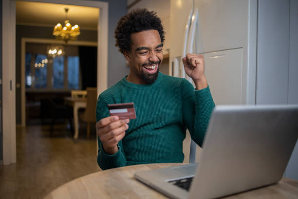 istock Cheerful man doing online shopping 1554523081