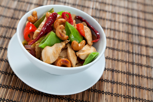 Chicken with cashew nuts, chili, peas, capsicum on white background