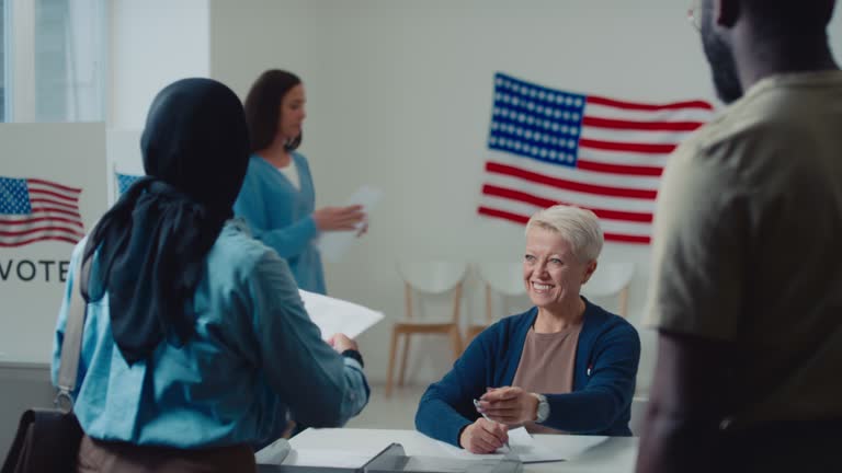 Caucasian Female Clerk Giving Ballots to People on Election Day