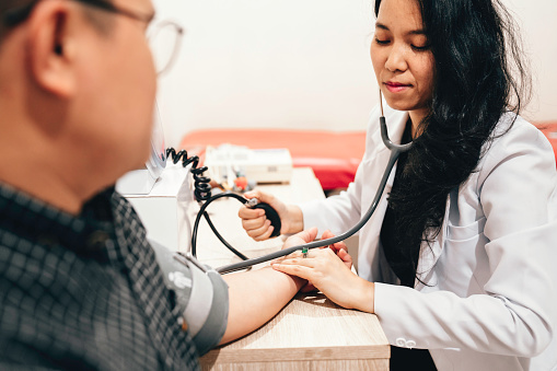 Doctor using a blood pressure gauge on arm of patient at medical clinic