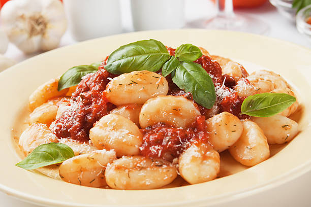 A closeup of gnocchi, topped with tomato sauce and basil stock photo
