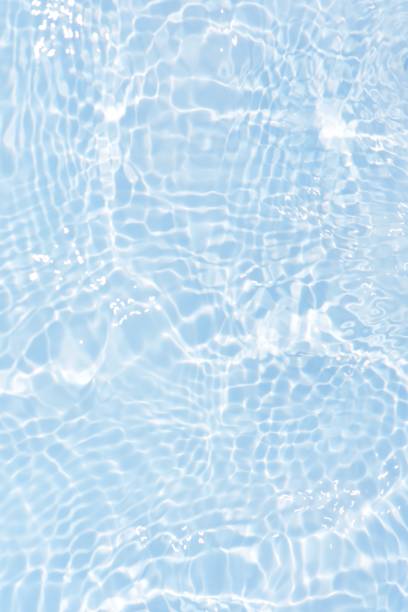 istock Blue water with ripples on the surface. Defocus blurred transparent blue colored clear calm water surface texture with splashes and bubbles. Water waves with shining pattern texture background. 1554626695