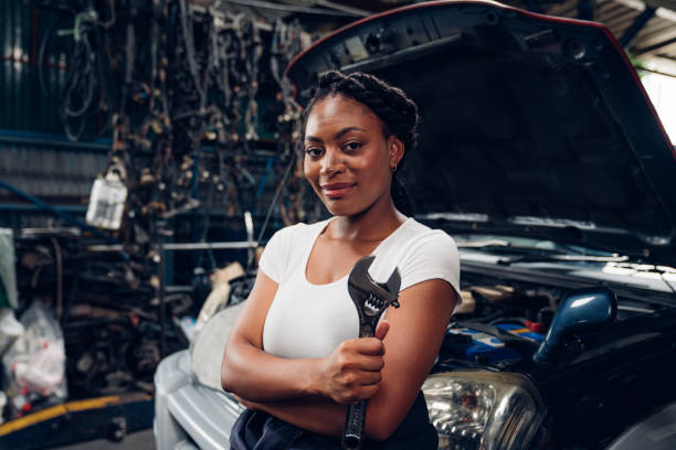 カメラを見ながら自動車修理工場で働く女性の自動車整備士のポートレート。 - mechanic auto mechanic wrench auto repair shop ストックフォトと画像