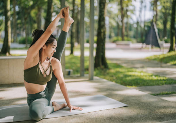 istock Asian Chinese woman practicing yoga in public park weekend morning 1554792105