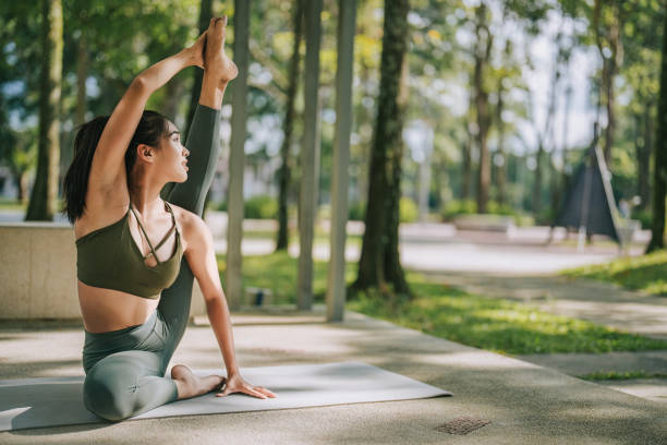 istock Asian Chinese woman practicing yoga in public park weekend morning 1554792108