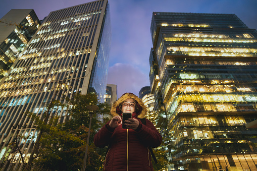 Woman using smartphone in financial district in winter