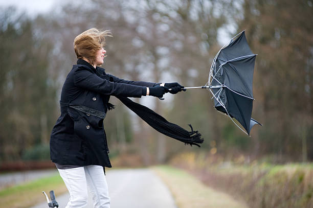 Fighting against the wind A young woman is fighting against the storm with her umbrella wind stock pictures, royalty-free photos & images