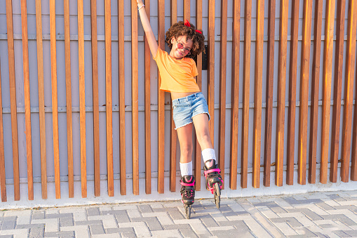 Latin kid riding on roller skates, in residential street in her neighborhood