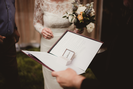Close up of wedding bands and written wedding vows during a wedding ceremony