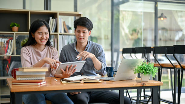 istock Two happy young Asian college students are looking at a tablet screen together 1554894399