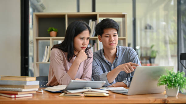 istock Two serious and focused Asian college students are looking at a laptop screen and discussing work 1554894404