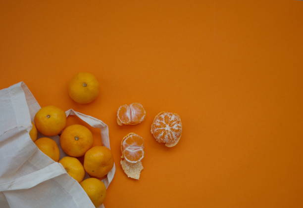 istock Tangerines in textile bag against orange background 1554923154