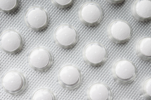 Close up of pills of blister pack on table .