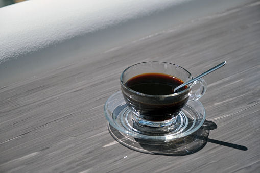 Goiania, Goias, Brazil – May 11, 2021: A clear glass cup with coffee on a reflective surface.