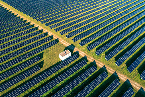 Aerial view of rows of blue solar panels in a large solar power plant.