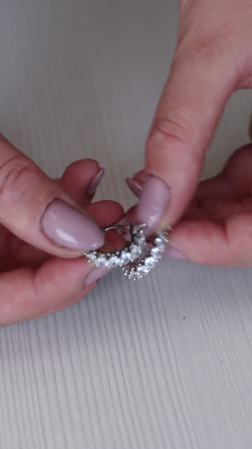 A woman shows off her earrings. vertical video. Close-up.