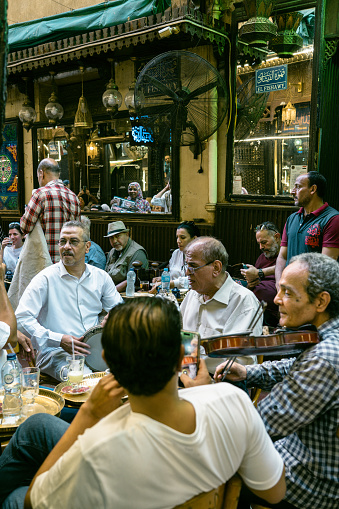 07/14/2023,Cairo,Egypt:Musicians playing traditional music for tourists outside of a sidewalk cafe at Khan al-khalili market in Cairo.Khan al-khalili is the most famous and largest market in Arabia.Traditional mosque and church can be seen in the background.