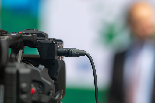 Close-up shot captures a TV camera recording a press conference, delivering impactful media coverage and capturing the essence of the event