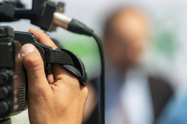Female reporter at press conference, writing notes, holding microphone