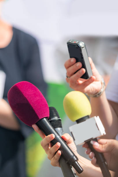 Journalists with microphones gather at an event for a green agenda press conference, delivering comprehensive coverage and capturing environmental initiatives.