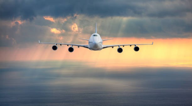 istock Airplane flying over tropical sea at sunset 1555048987