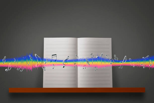 Blank sheet music with silver musical note and multicolor sound wave on a wooden shelf, against dark concrete wall with copy space.
