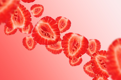Levitation of strawberry halves on a red background.