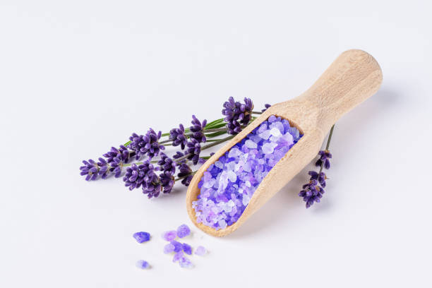 Lavender bath salt with lavender flowers on white background. Lavender herbal sea salt for spa aromatherapy and body care.