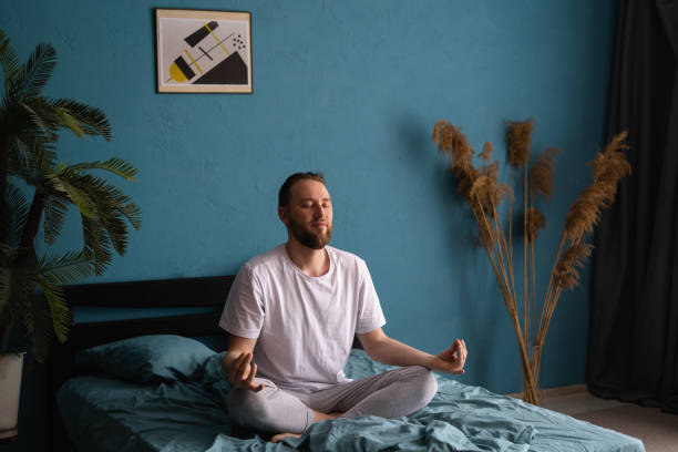 istock Morning meditation concept. Millennial man practicing yoga on bed after waking up 1555117054