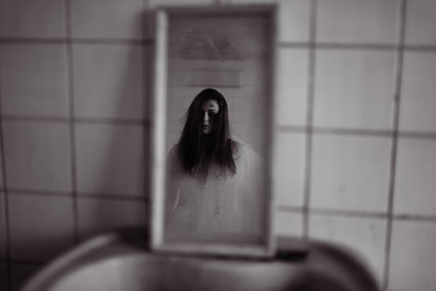 horror movie scene with a creepy face in the mirror, dead bride in white dress looking reflection. halloween scene - mirror women reflection ghost imagens e fotografias de stock