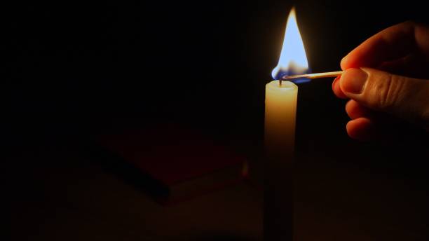 istock The bright flame of a candle illuminates an ancient book lying on the table. 1555119687