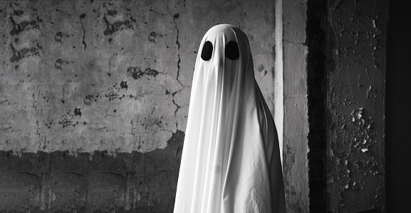 White ghost on gray wall background. Halloween spooky concept. Banner. Copy space