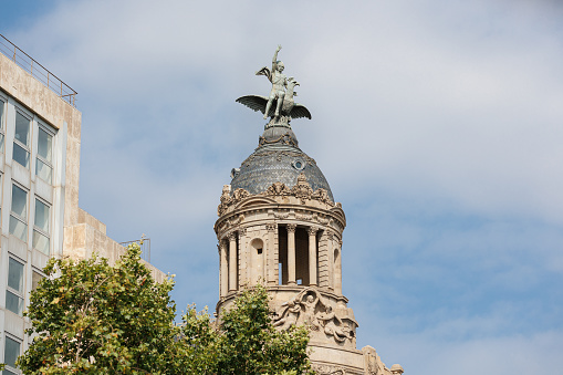 The Dome and top Statues of La Union and el Fenix on Passeig de Gracia, a Residential and office Building, Barcelona - Spain.